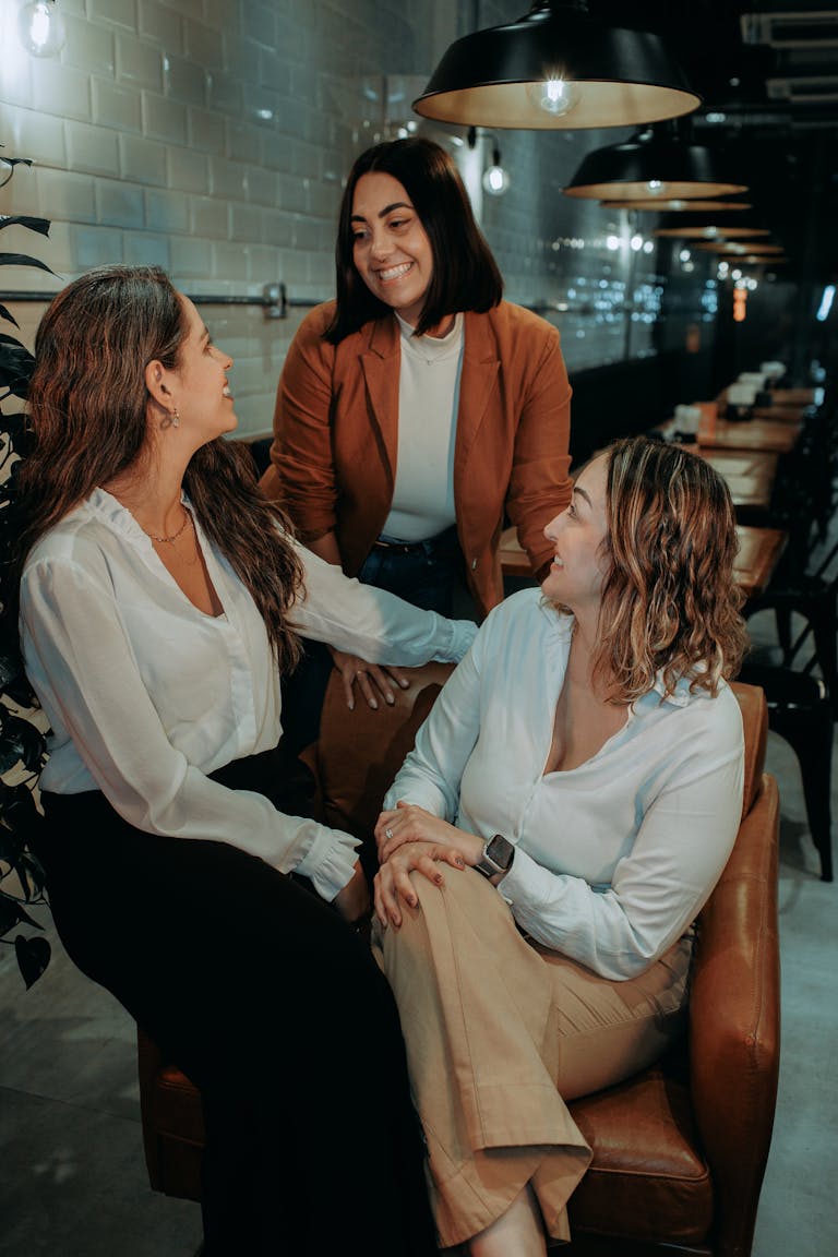 A group of three diverse women enjoying a casual business meeting in a cozy cafe setting.